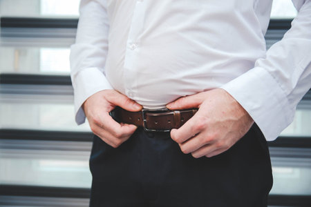 A male fixing his belt on the trousersの写真素材