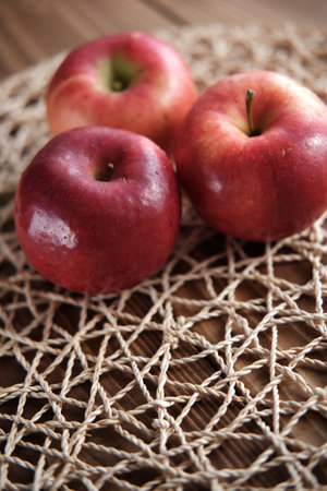 A vertical shot of red juicy apples on woven textureの写真素材