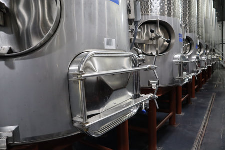 A shot of a row of stainless steel tanks containing wine at a winery
