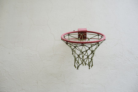 A basketball hoop with net against a white wall outdoorの写真素材