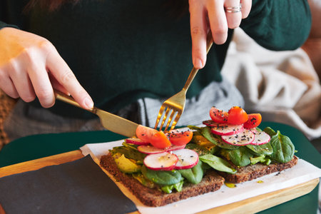A closeup shot of female hands eating vegetable sandwiches