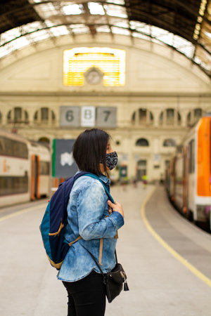 A vertical shallow focus closeup of a female standing in the train station in Barcelona, Spainの写真素材