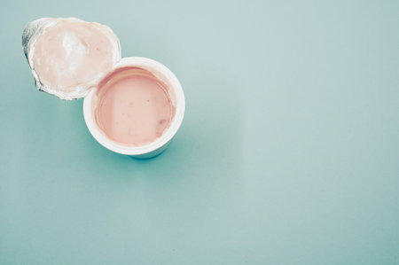 A top view of an opened plastic container of fruit yogurt on a blue surfaceの写真素材