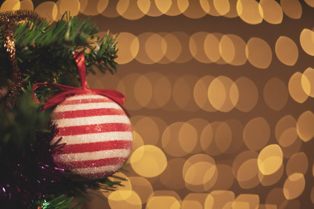 A closeup shot of a red Christmas ornament on a background with bokeh lightsの写真素材