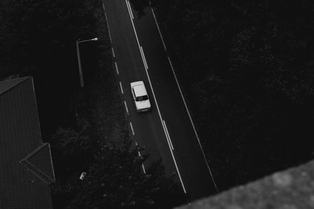 A high angle shot of a car on a street surrounded by treesの写真素材