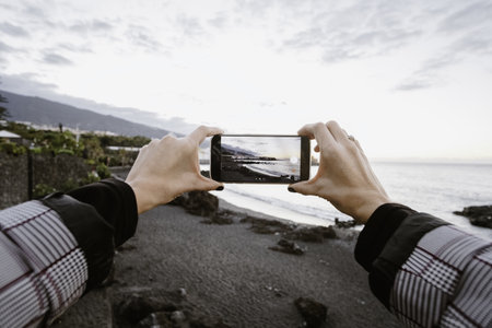 A view of a woman taking a picture through his phone of the seaの写真素材
