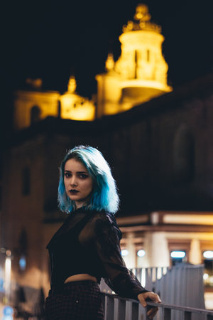 A miserable female with blue hair standing on a bridge at nightの写真素材