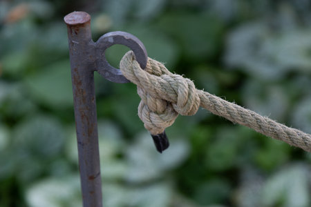 A closeup of a thick rope knot tied to a piece of metal