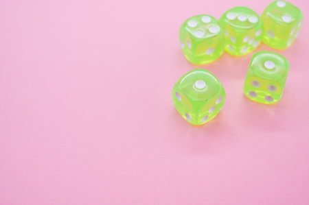A top view closeup of five neon green dice isolated on a pink backgroundの写真素材