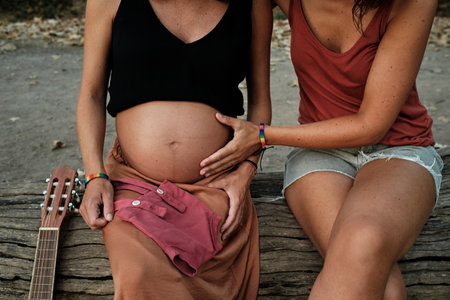 A closeup of a pregnant lesbian couple doing a photoshoot in a parkの写真素材