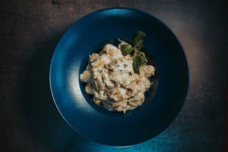 a top view of a chicken salad with champignons on a dark blue plateの写真素材