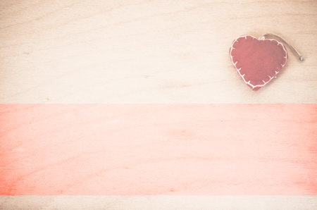 An overhead shot of hand made red felt heart decoration on a natural wood backgroundの写真素材