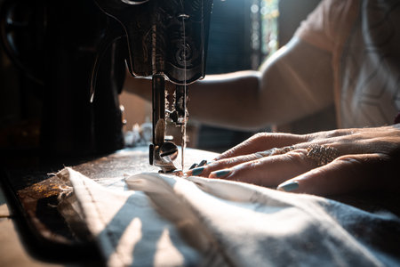 A closeup of an old woman hands using a sewing machineの写真素材