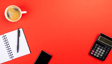 The flat lay of the office working tools on the red surface - space for textの写真素材