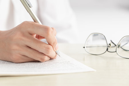 A hand of businesswoman writing on paper in the officeの写真素材