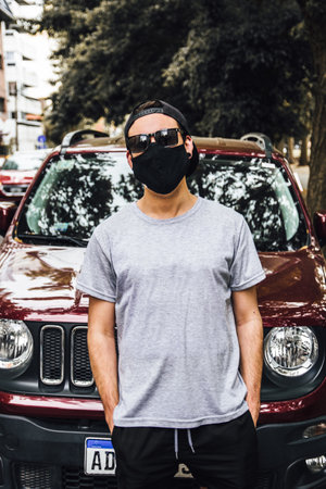 A vertical shot of a cool young man outdoors wearing a face mask - concept of the new normalの写真素材