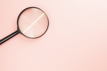 A top view of a magnifier placed on a light pink surfaceの写真素材