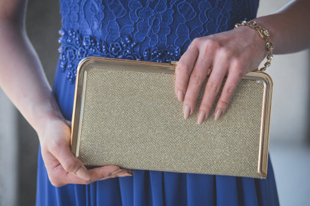 A closeup shot of a female in a fancy evening dress holding a clatch bag