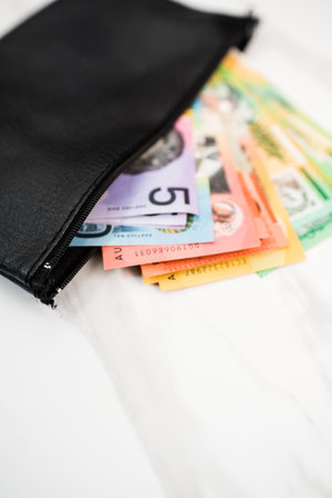 a vertical shot of Australian dollar banknotes in a black wallet on the white backgroundの写真素材