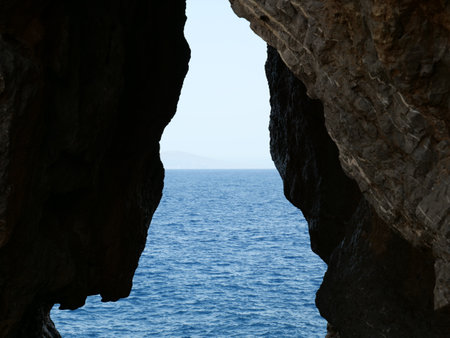 The calm sea captured from inside the cliffs during the daytime in Crete, Greeceの写真素材