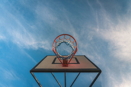 A low angle shot of a basketball hoop with blue sky in the backgroundの写真素材