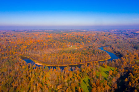 An aerial shot of Gauja river in Latvia surrounded by trees in autumnの写真素材