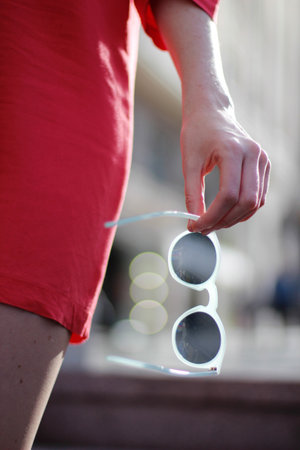 A vertical shot of a female with a red dress and white sunglassesの写真素材