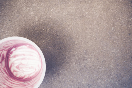 A top view closeup of an empty container of a purple yogurt on a grey-toned rough stone surfaceの写真素材