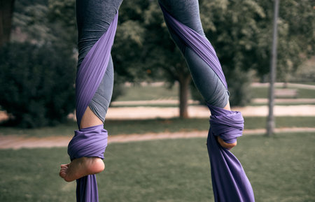 A young Caucasian woman doing aerial yoga with hammocks in the parkの写真素材