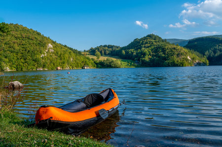 The kayak on the wavy lake surrounded by hills covered in greens in the parkの写真素材