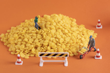 A closeup shot of miniature labor figures on a pile of corn on orange backgroundの写真素材