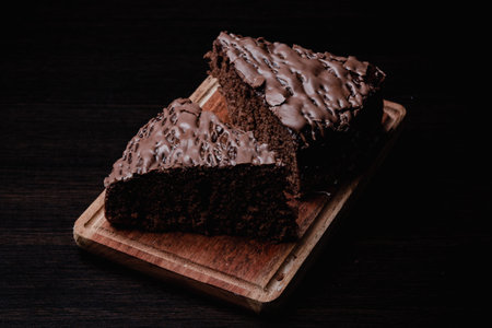 A closeup of two pieces of tasty chocolate cake on a wooden boardの写真素材