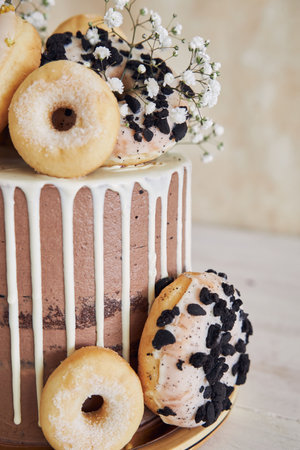 A vertical closeup shot of delicious Donut choco Birthday cake with donuts on top and white drip