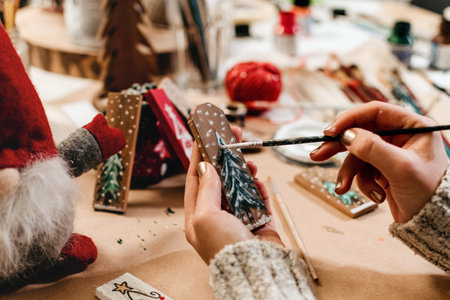 A female hand painting on a tree on a wooden stick on a Christmas ornaments backgroundの写真素材
