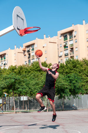 A vertical shot of a young man throwing ball into the basketball basketの写真素材