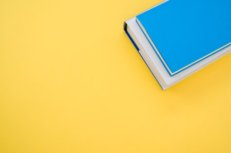 A top view of the hardcover books on the yellow surface - space for textの写真素材
