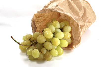 A closeup shot of grapes in a paper bag on a white backgroundの写真素材
