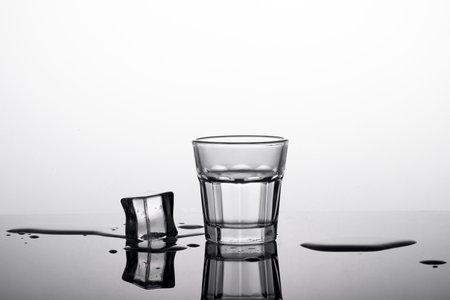 A shot of a glass of whiskey with a piece of ice on the sideの写真素材