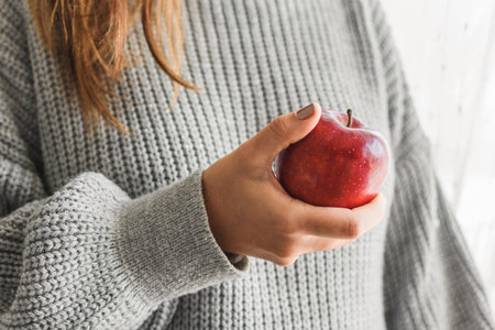 A closeup shot of a female hand holding a red appleの写真素材