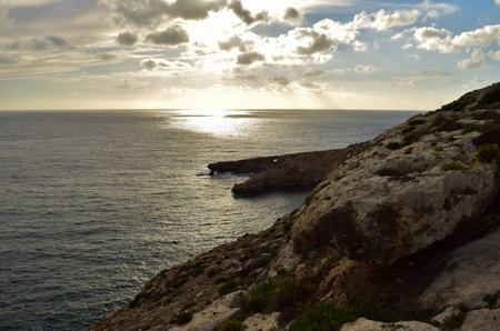 The coastal fault and erosion formations in the Maltese Islands, during sunset. The small island of Filfla in the distance.の写真素材