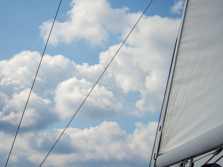 A cloudy sky and white fabric of a sailboat