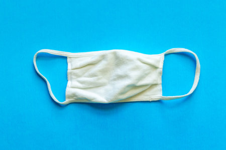 A white cloth face mask is isolated on a blue background