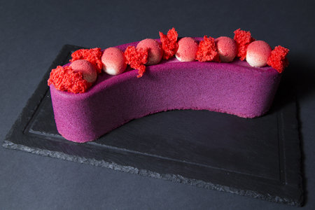A closeup of a purple mousse cake with velour coating and pink mousse ballsの写真素材