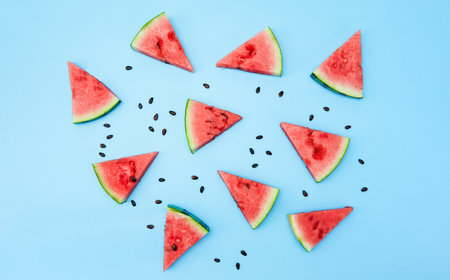 A top view of sliced watermelons with seeds isolated on a light blue surfaceの写真素材