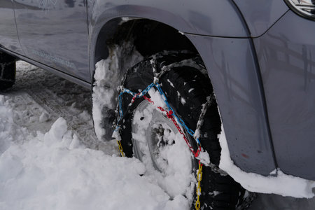 A shot of a car wheel deep in snow with chains on it