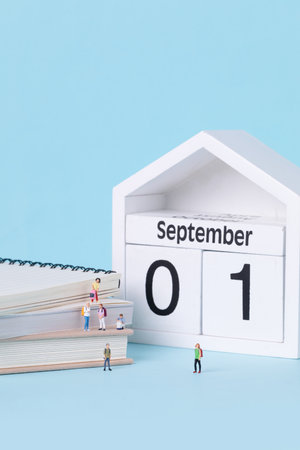 A vertical shot of figurines of students standing on and around textbooks. The first day of school