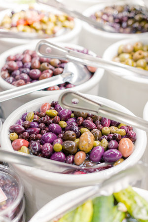 A closeup of colorful olives stored in a white pack at the storeの写真素材