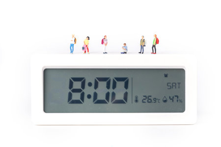 A closeup shot of little figurines of students standing on a digital alarm clockの写真素材