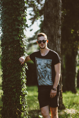 A vertical selective focus shot of a handsome guy in a parkの写真素材