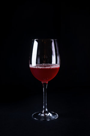A vertical shot of a glass of red wine on a black background